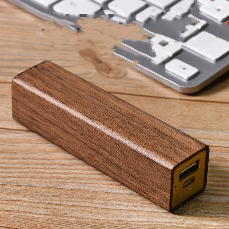 Brown black walnut wood portable power bank showing size next to a charging cable