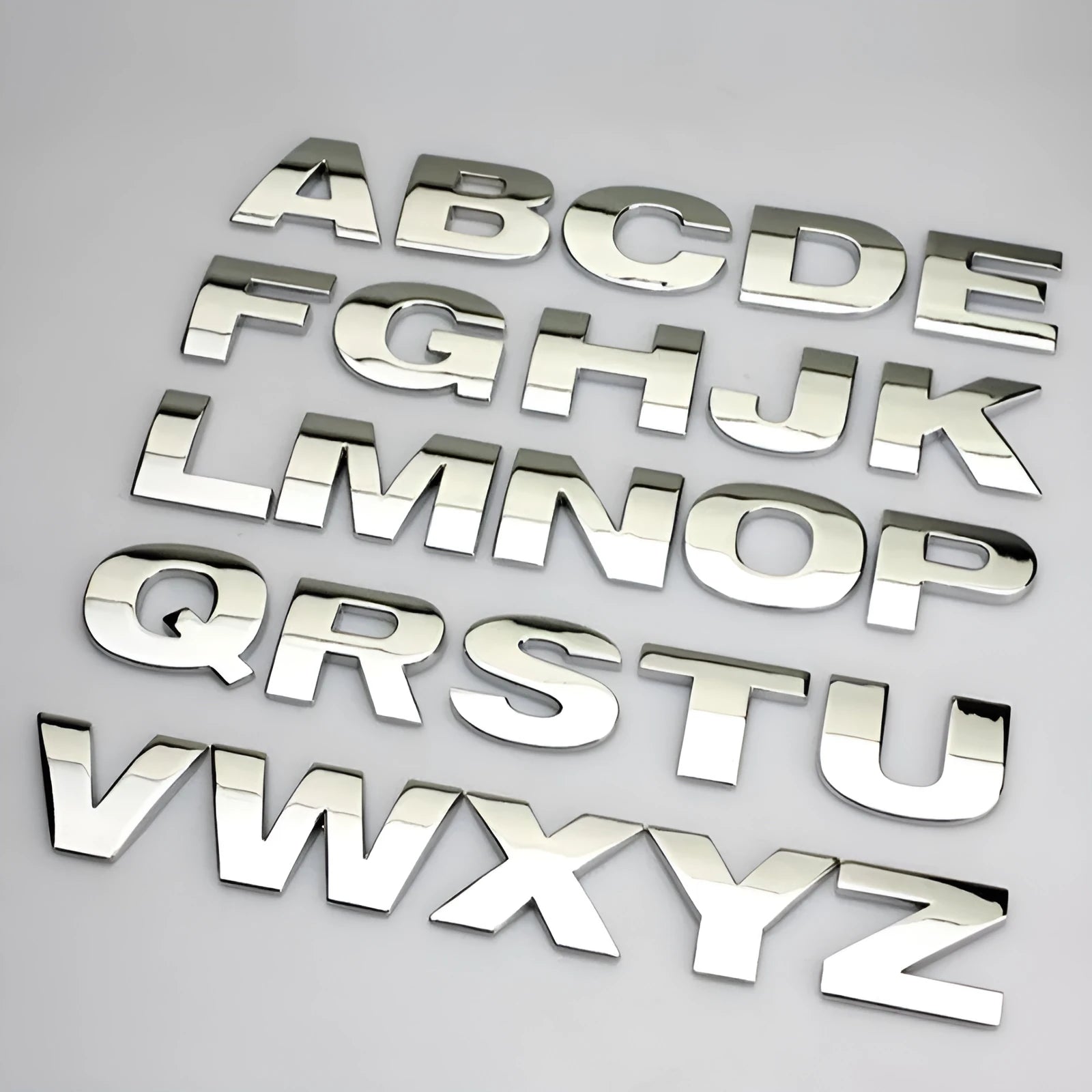 Close-up of a silver zinc alloy 3D raised letter 'A' car bumper sticker, approx 2.5cm tall.