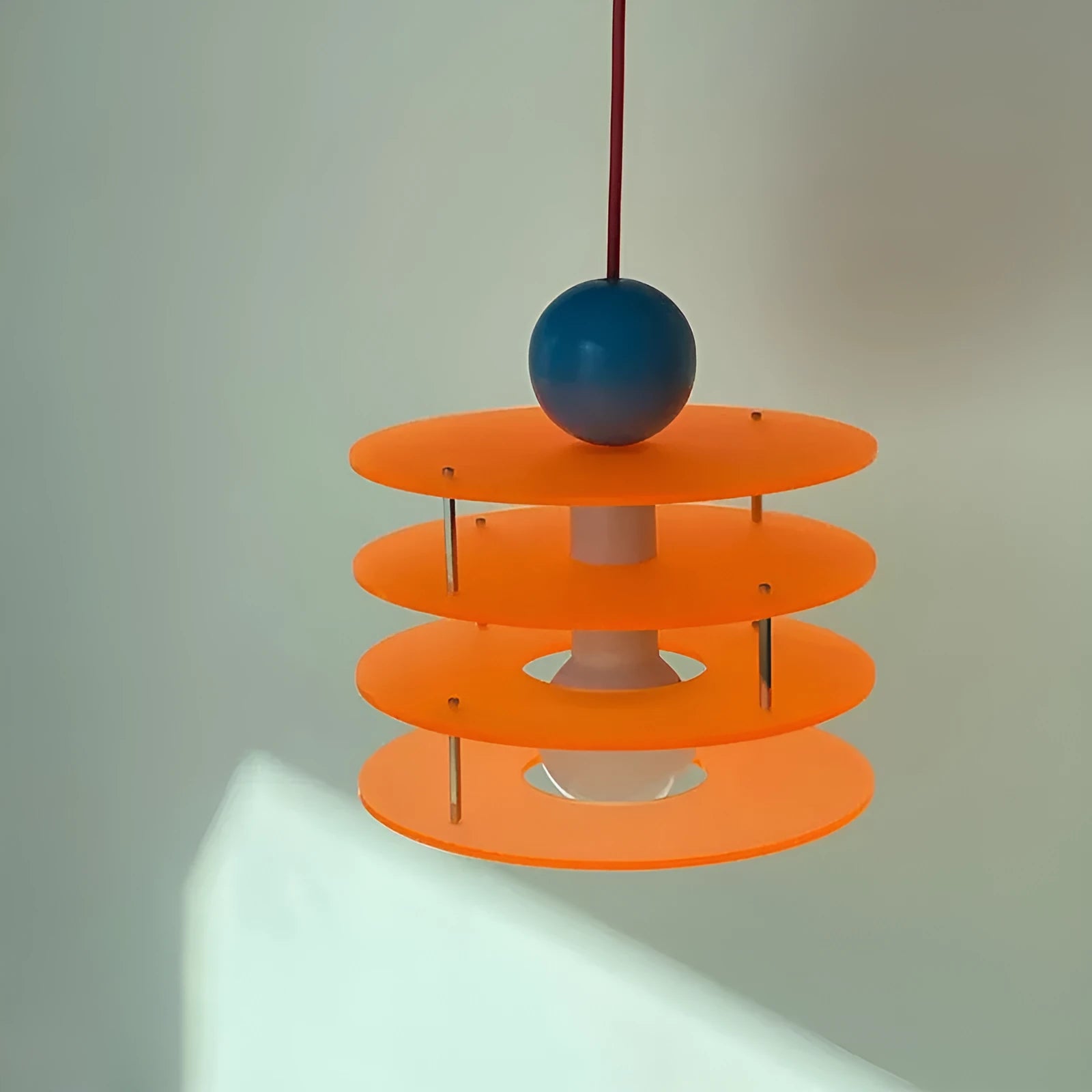 Modern macaron-shaped PH5 chandelier with a frosted shade, shown in a restaurant setting.