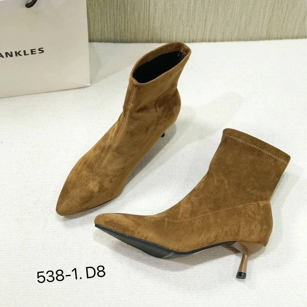 Black pointed toe stiletto ankle boots with a mid-calf sock length on a model.
