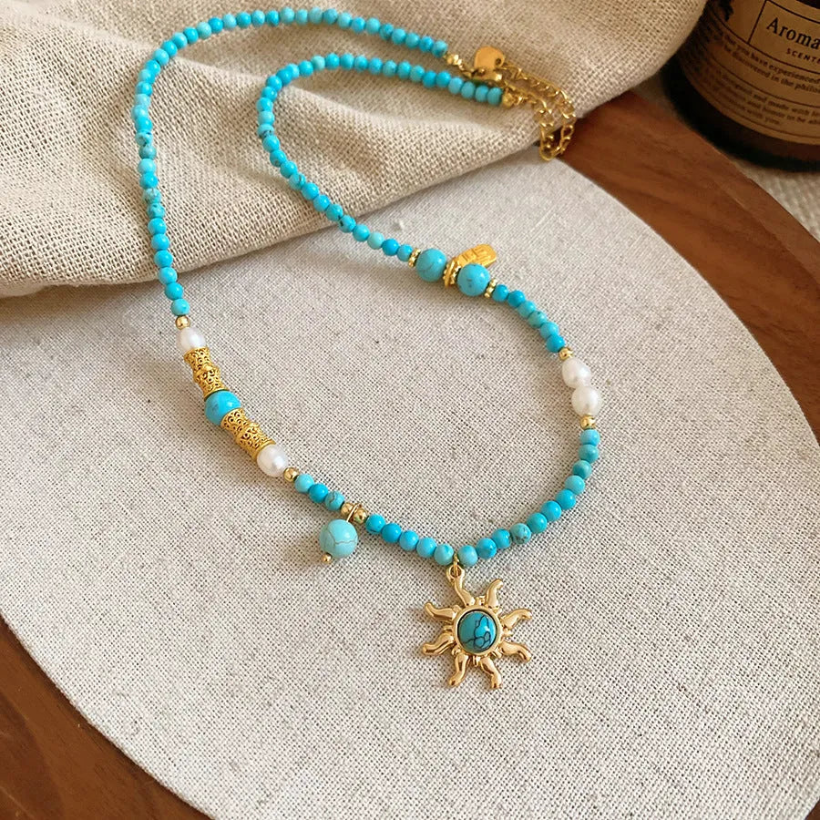 Sun necklace with a stone geometric pendant and freshwater pearls on a clavicle chain.
