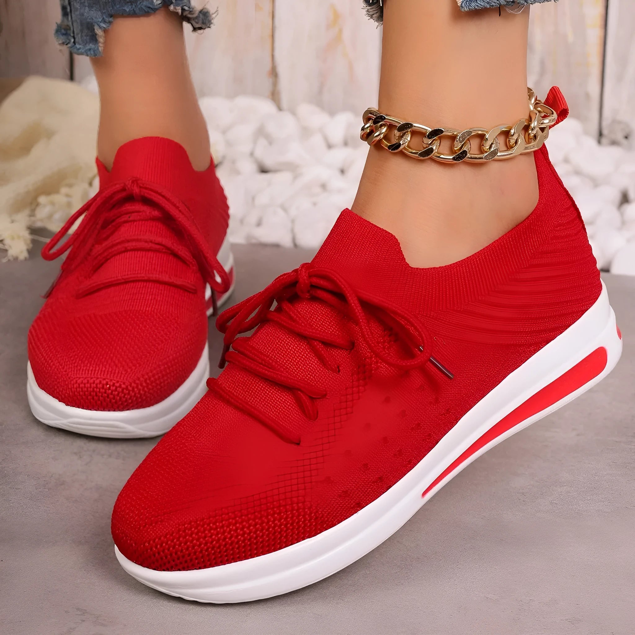 Women's low-top fly-knit sneakers in red, with a round toe and front lace-up closure on an injection-moulded sole.