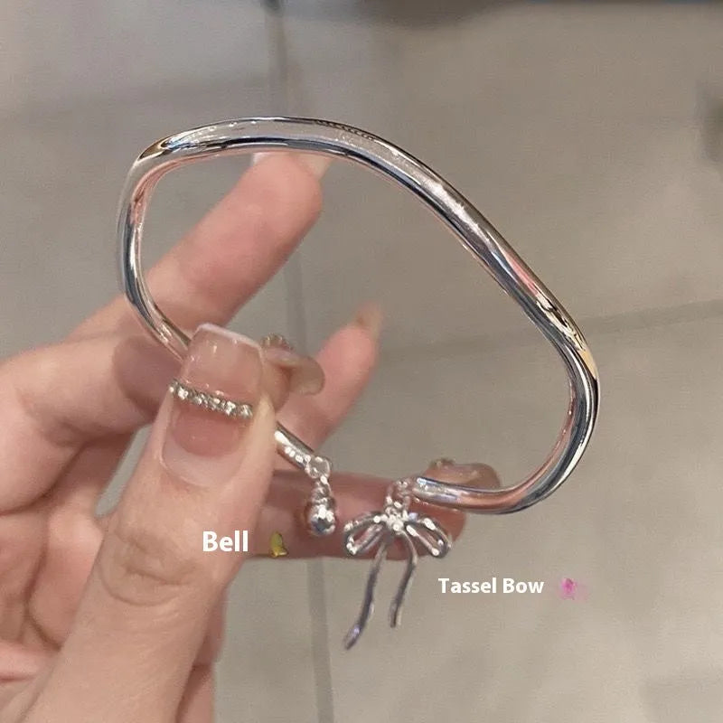 Silver adjustable bracelet with a fixed bow charm on a wrist.