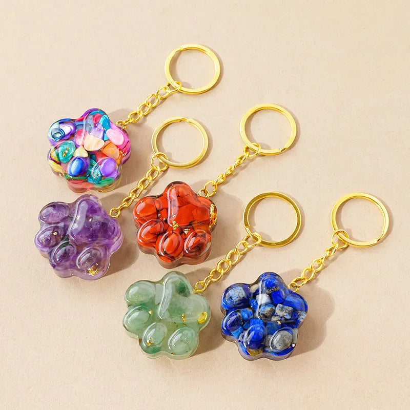 Natural crystal cat's paw shaped keychain charm on a keyring, showing colour variations of different gemstones.