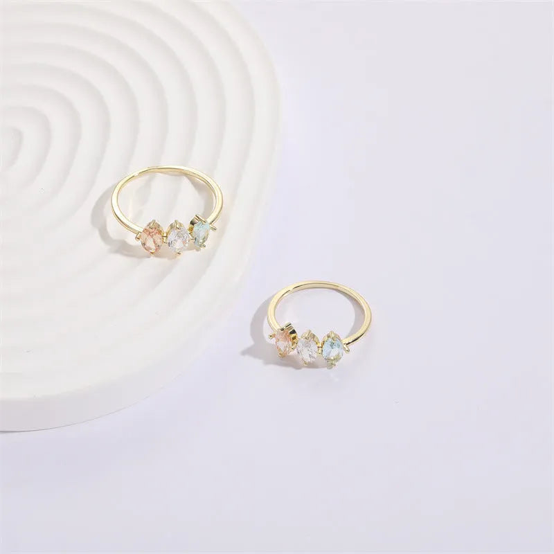 Gold geometric women's ring with horse eye design and three coloured zircon stones on a triangular band.
