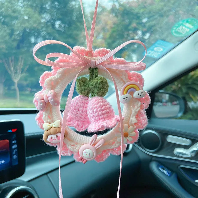 Handmade woven wool bell orchid car pendant on a green background, showing textured detail.