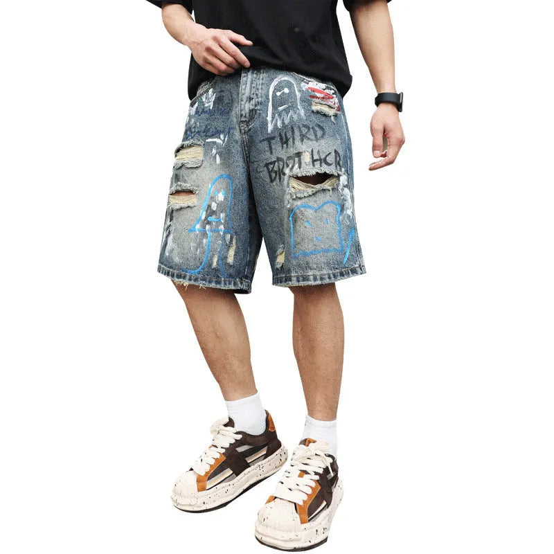 Blue men's ripped denim shorts with a graffiti pattern and zipper fly, laid flat.