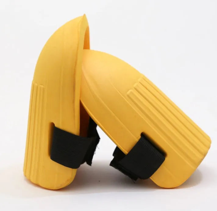 A pair of rectangular EVA foam knee pads in army green colour, shown on a garden soil background.