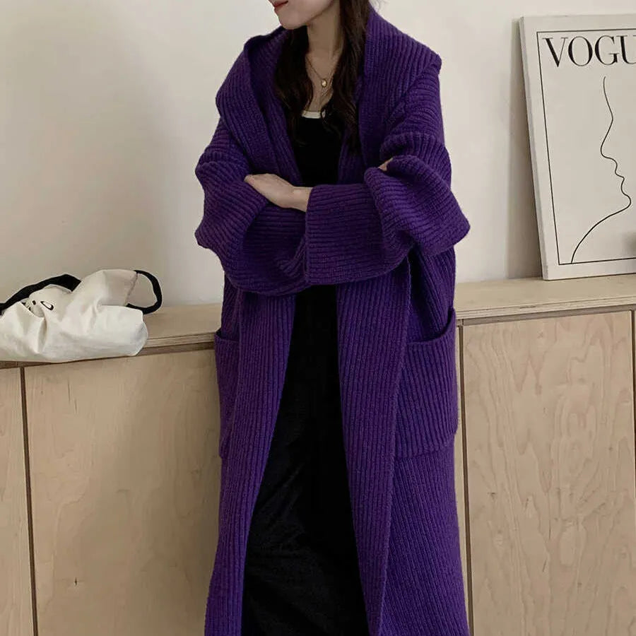 A long, loose grey hooded cardigan coat for women on a hanger, showing its length and raglan sleeves.