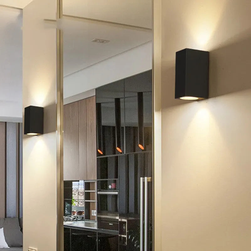 Satin black aluminium and glass LED wall lamp mounted on an interior wall.