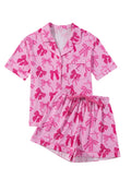 Pink women's two-piece pajama set with bow print, featuring a top and matching trousers.