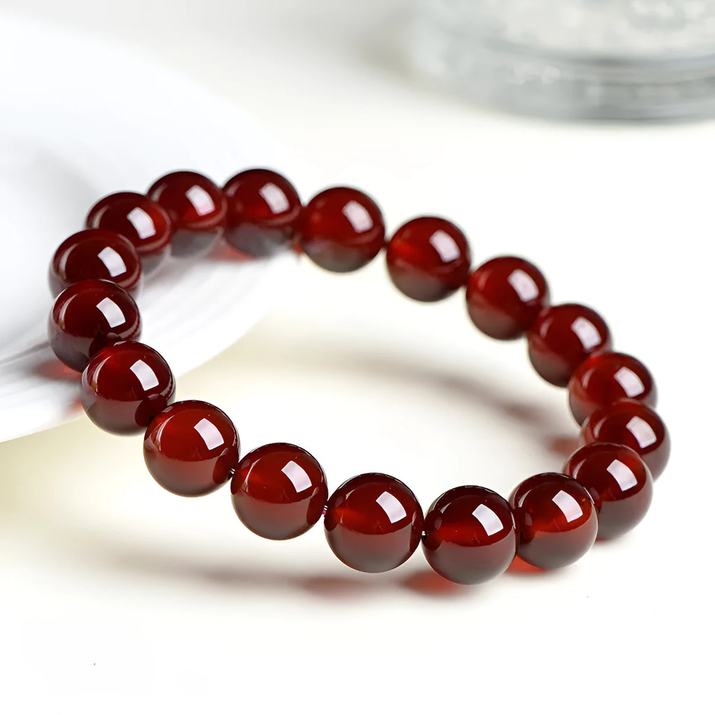 Natural orange red garnet crystal bead bracelet with a ruyi charm on a wrist.