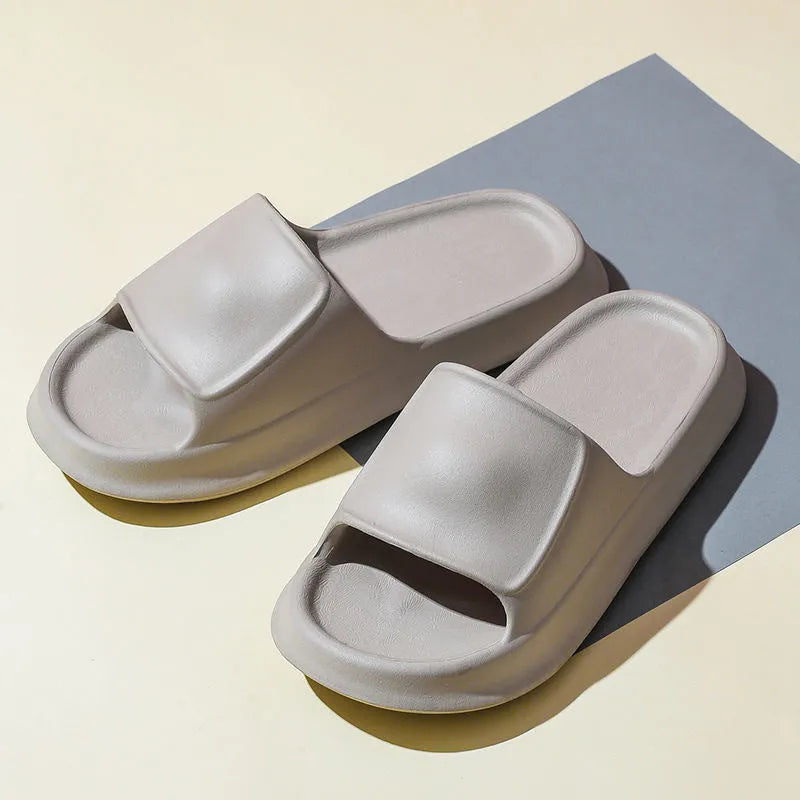 Pair of thick-soled white EVA foam flip-flop slippers on a bathroom floor, showing non-slip tread pattern.