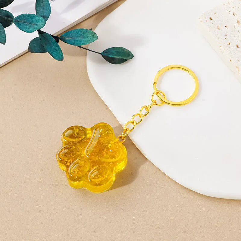 Natural crystal cat's paw shaped keychain charm on a keyring, showing colour variations of different gemstones.