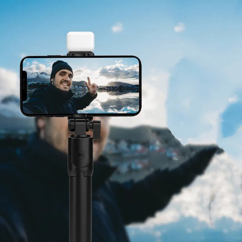 Black aluminium alloy Bluetooth selfie stick with extended tripod legs and phone holder attached.
