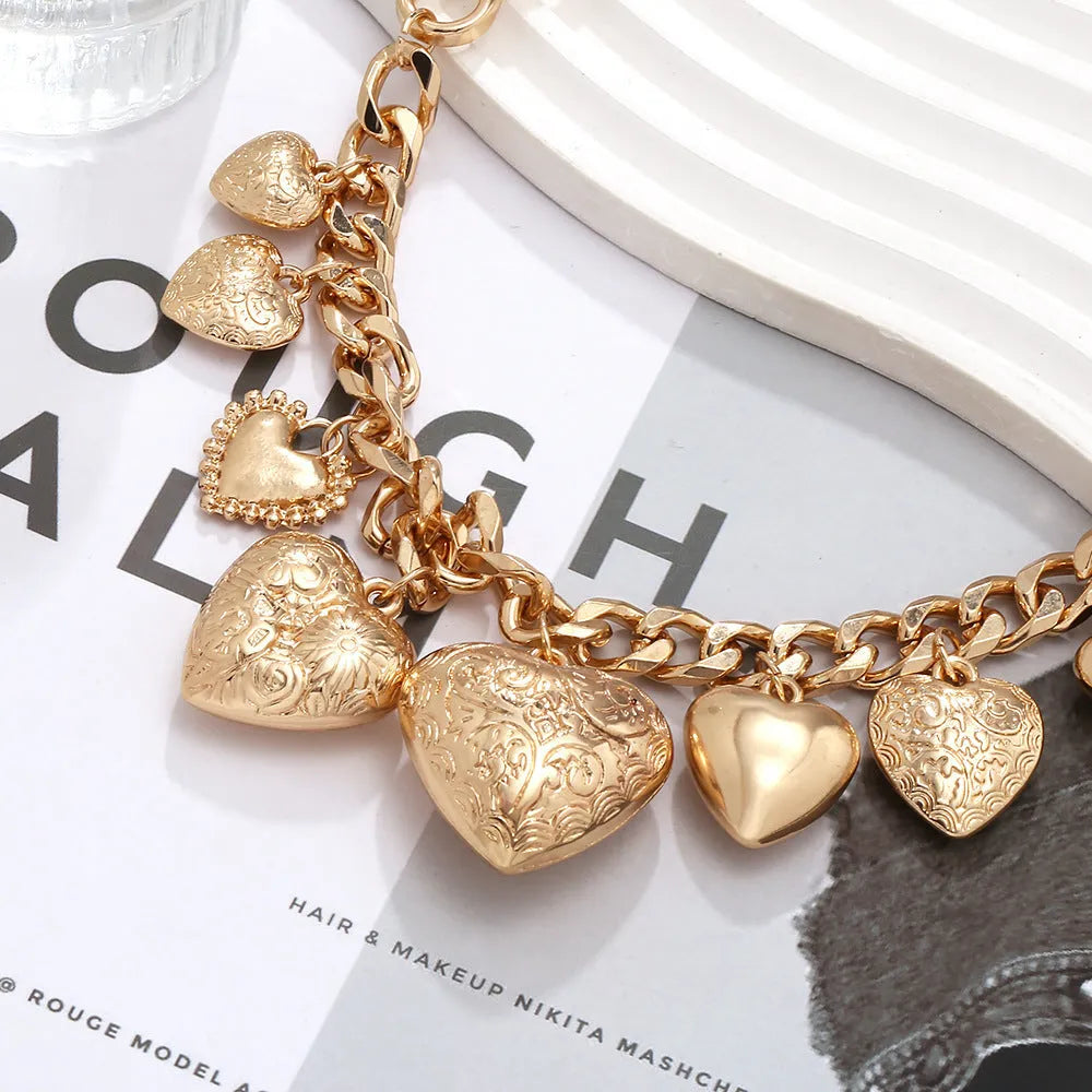 Carved heart-shaped alloy pendant on a metal chain necklace in gold colour.