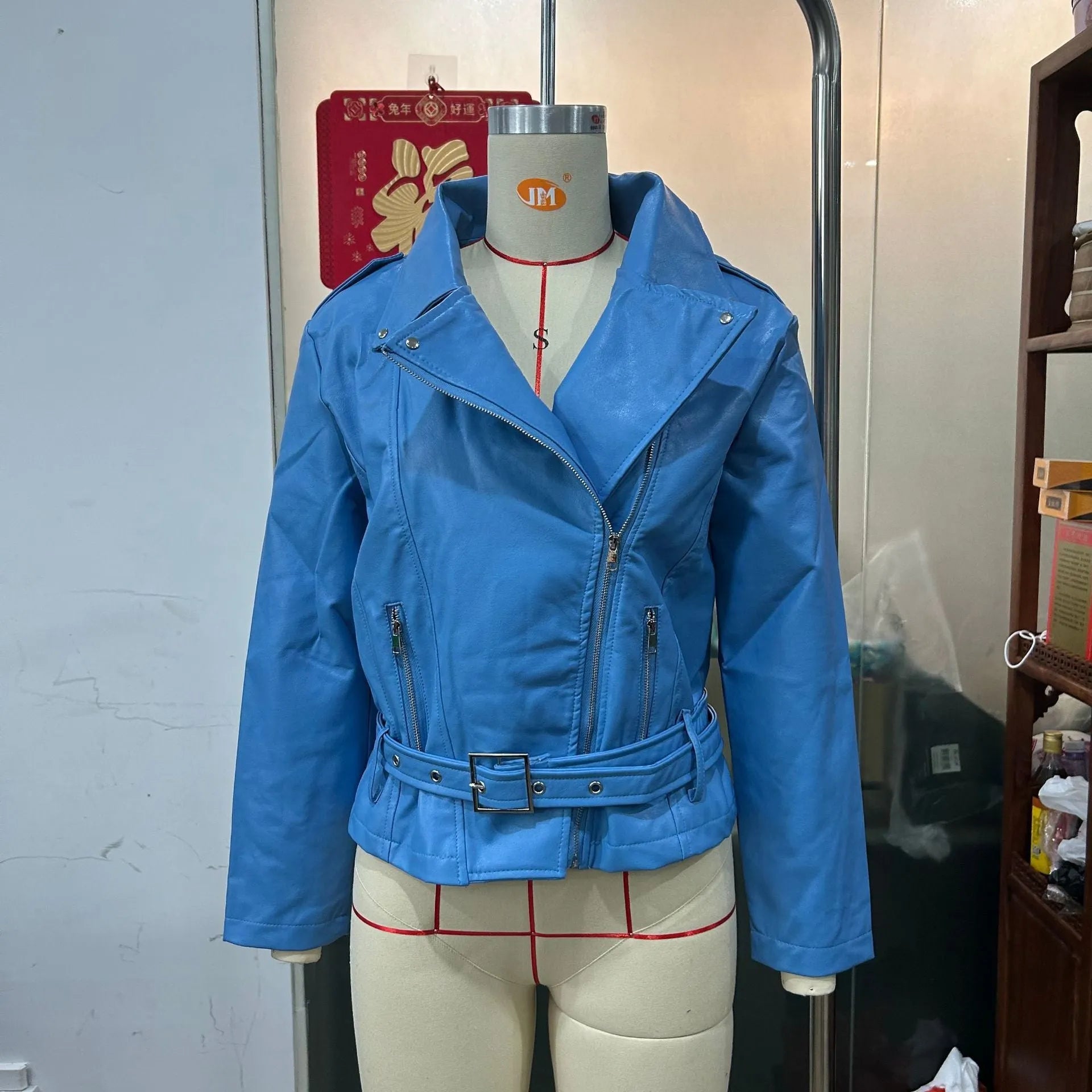 Black punk style short leather jacket with a Peter Pan collar and drawstring waist on a hanger.