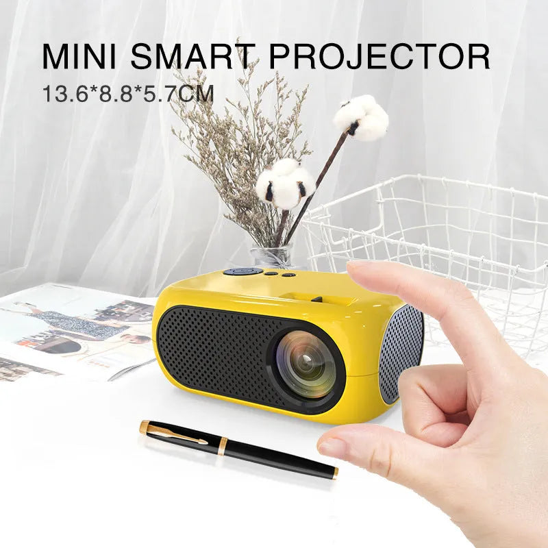 M24 Micro Mini LED Projector in Gold or White colour with power adapter and cables on a table.