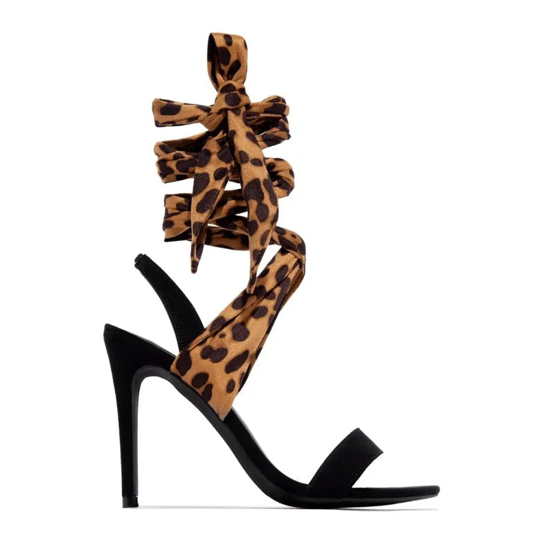 Light brown leopard print women's high heel sandals with cross-straps and a tall fine heel on a rubber sole.