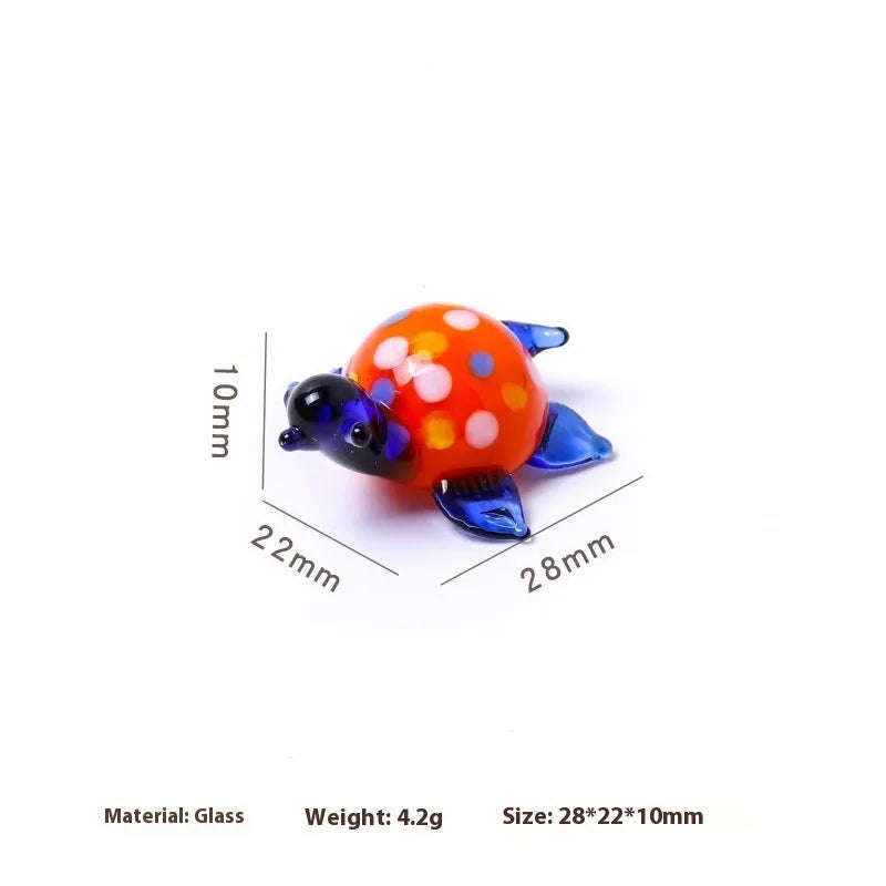 Geometric glass turtle ornament in a modern style with a coloured shell, displayed on a desktop.