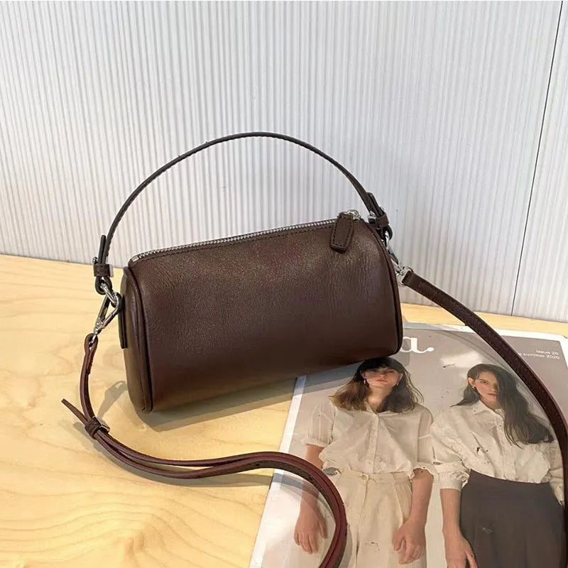 Soft genuine leather cylindrical crossbody bag in street style, shown in black, with a single strap.