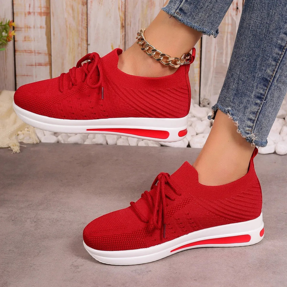 Women's low-top fly-knit sneakers in red, with a round toe and front lace-up closure on an injection-moulded sole.