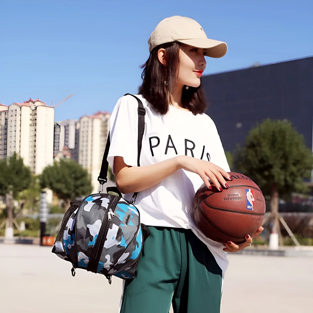 Black Oxford cloth basketball training bag with a single shoulder strap, shown next to a basketball.