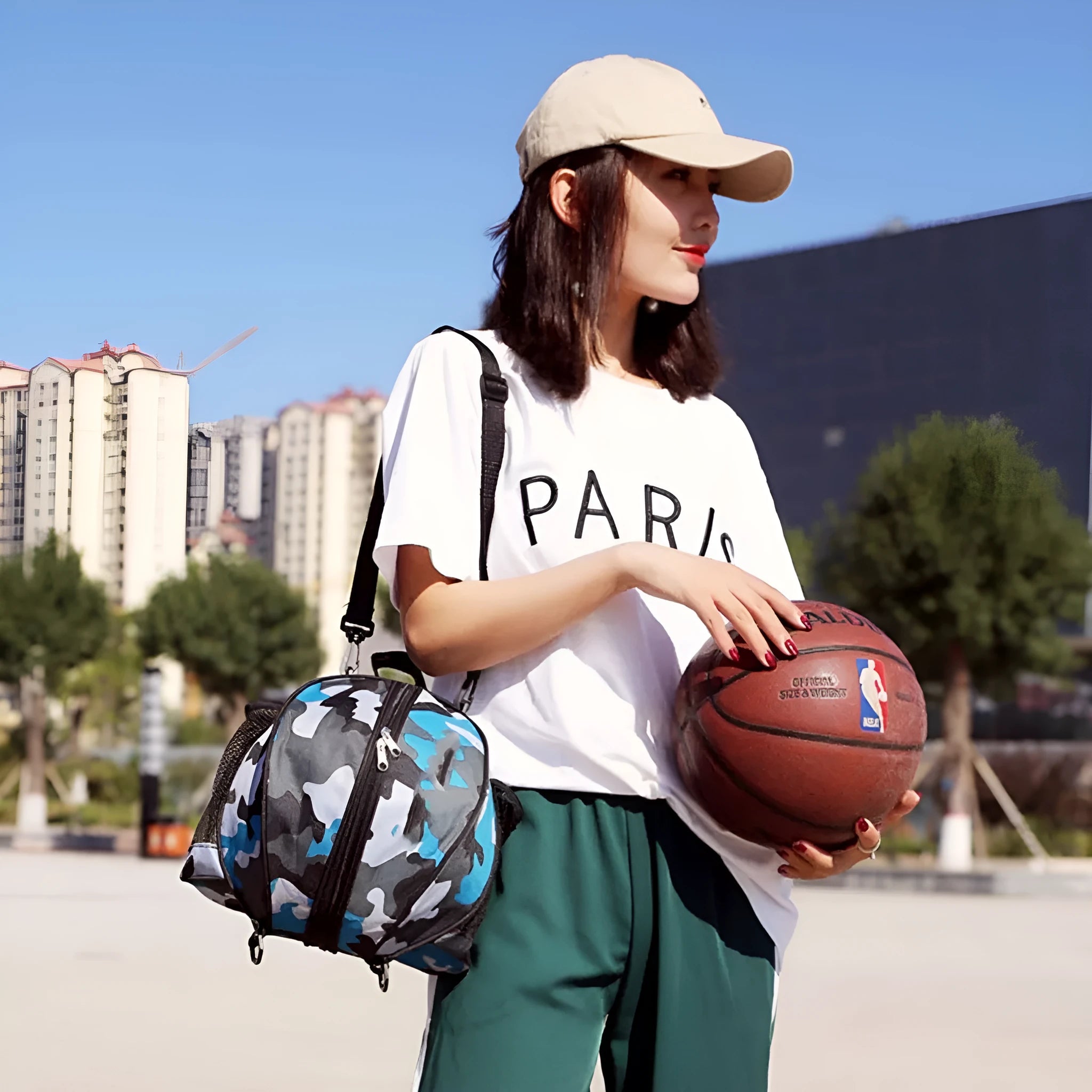 Black Oxford cloth basketball training bag with a single shoulder strap, shown next to a basketball.