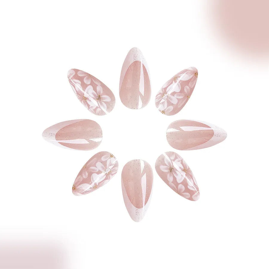 Short almond shaped false nails with French style gloss and glittering powder flower accents