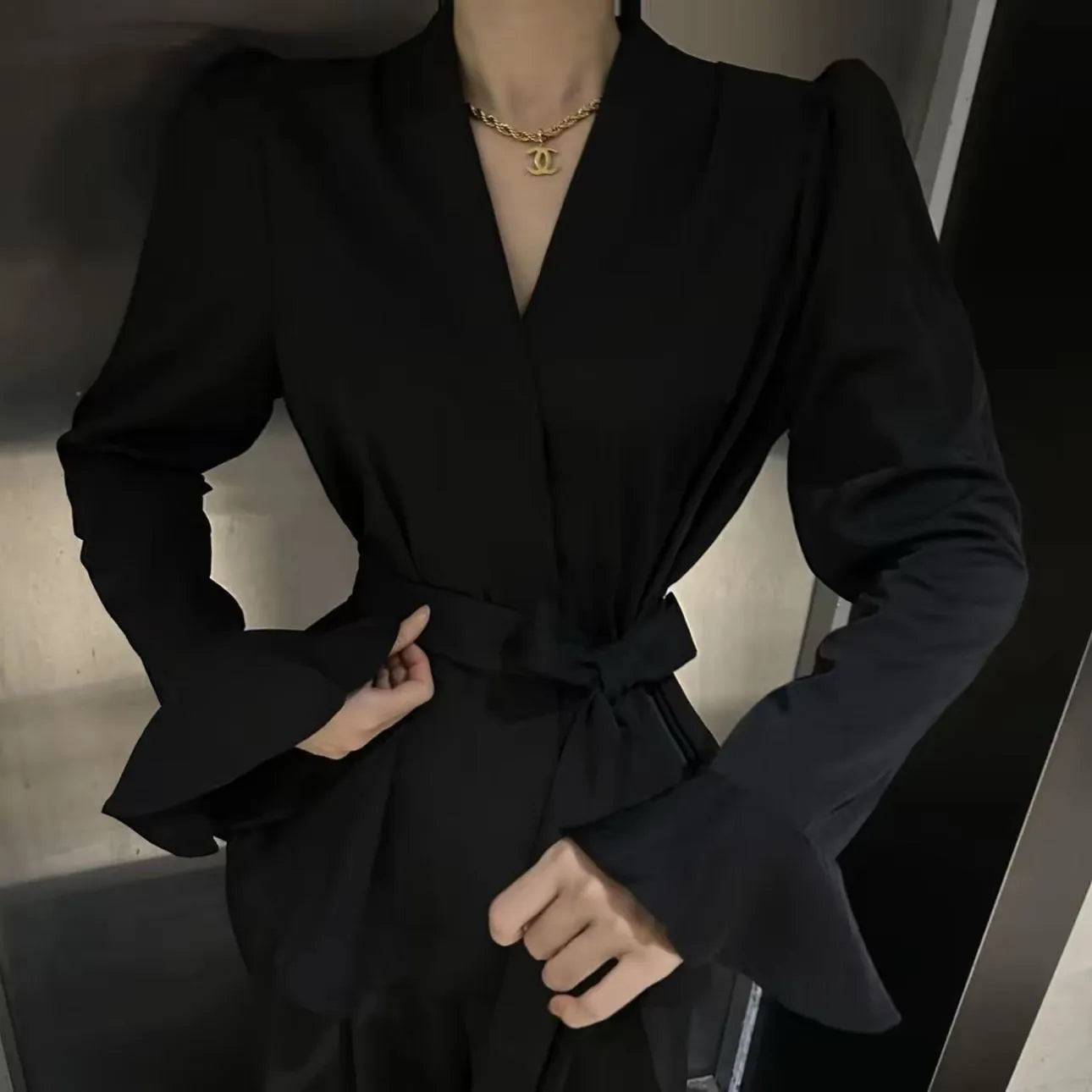 Women's black French-style tied shirt with an irregular collar and long bell sleeves.