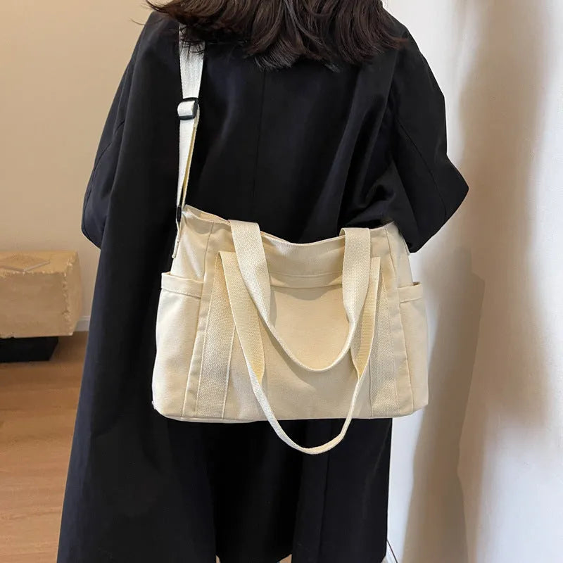 Large black polyester canvas shoulder tote bag showing outer sandwich pocket.