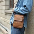 Men's brown genuine leather crossbody shoulder bag showing sewing line details.
