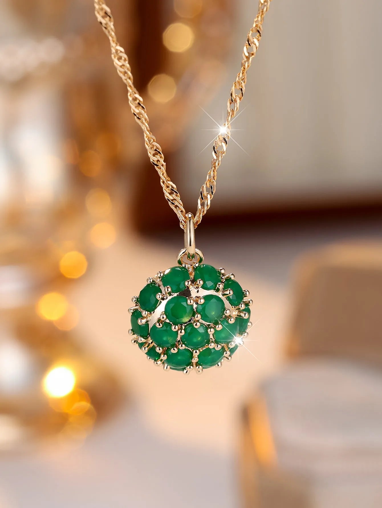 Champagne gold geometric pendant necklace with a round emerald stone and diamond accents on an adjustable chain.