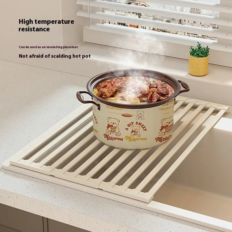 Milky white foldable stainless steel kitchen draining rack next to a sink.