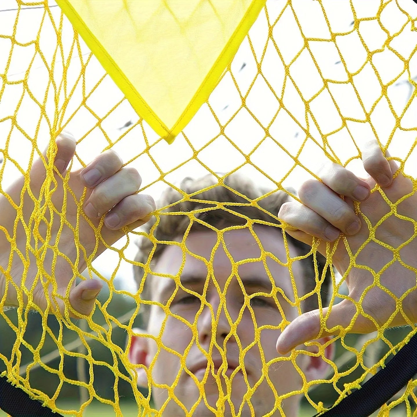 Portable black and yellow soccer training goal net set up on a grass field.