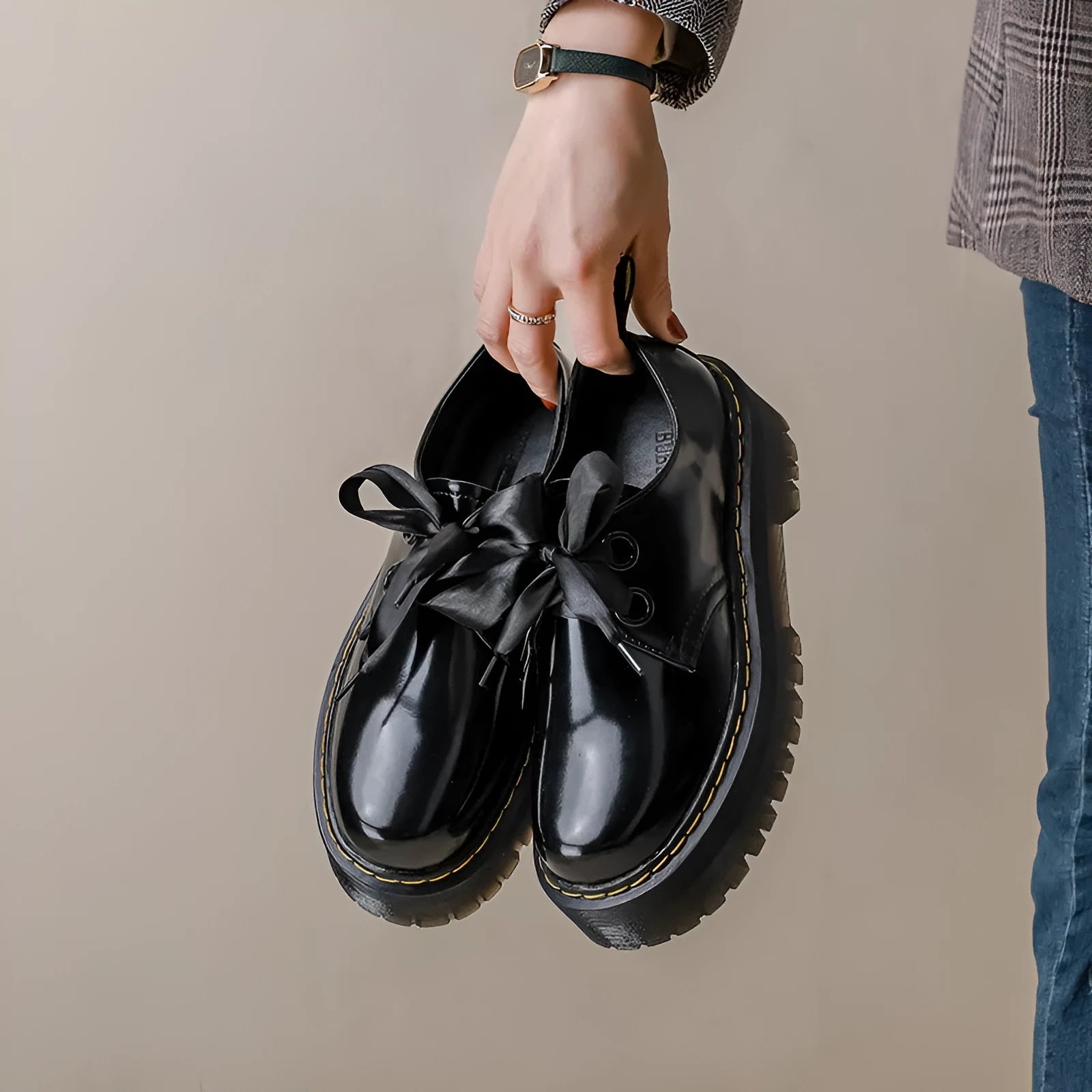 Black thick-soled women's lace-up shoes with ribbon and cross strap detailing on a white background