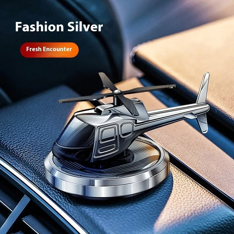 Silver metal solar-powered rotating helicopter car perfume ornament on dashboard