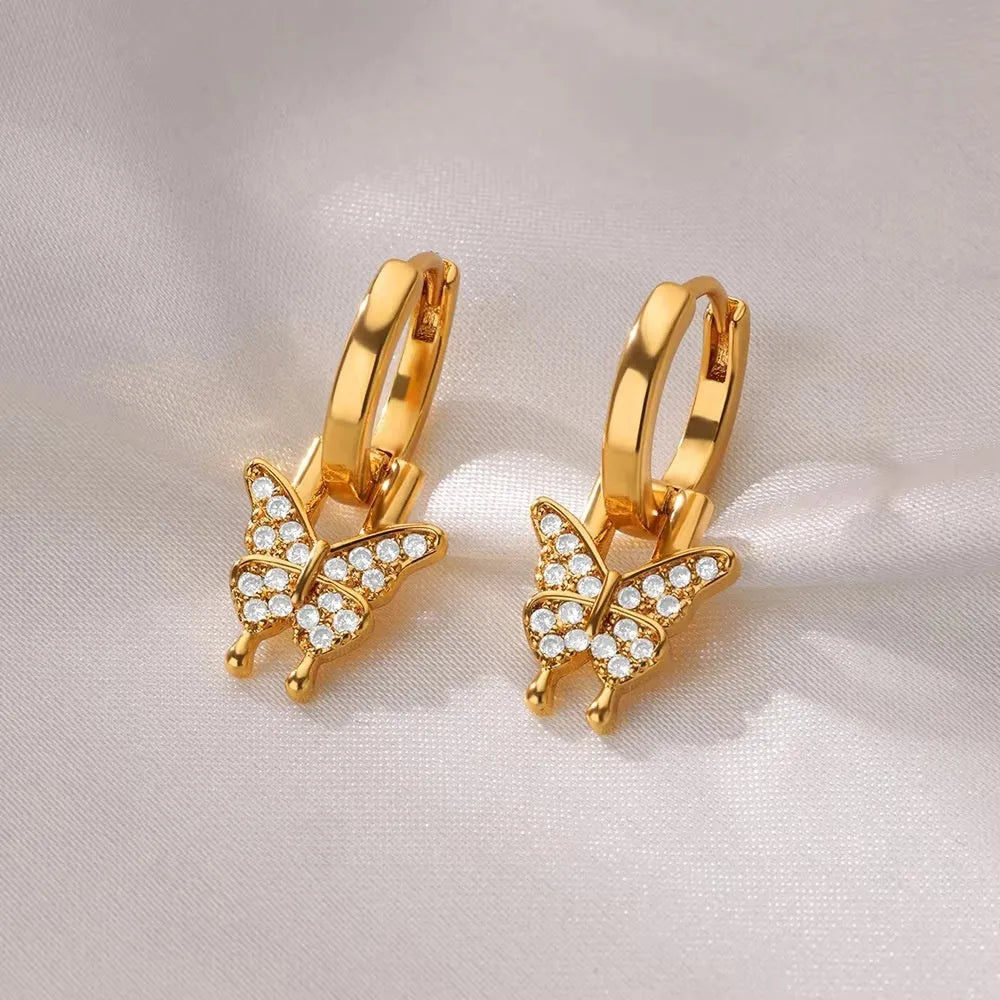 Butterfly-shaped copper earrings with geometric heart, star and bow patterns in metallic finish