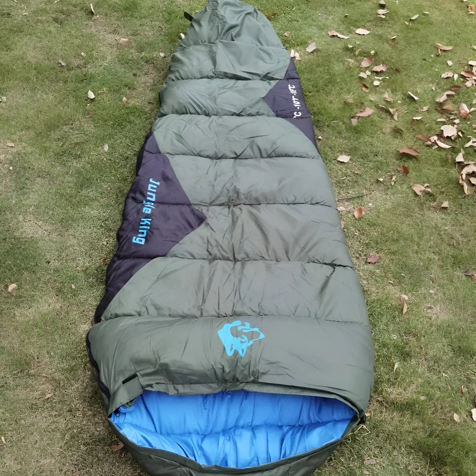 Outdoor cotton sleeping bag in army green, shown next to its grey compression storage sack