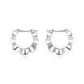 A pair of sterling silver geometric earrings with round details on a simple background.