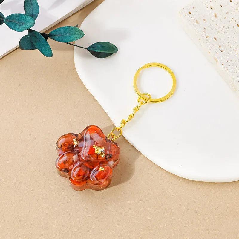 Natural crystal cat's paw shaped keychain charm on a keyring, showing colour variations of different gemstones.
