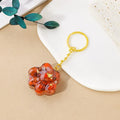 Natural crystal cat's paw shaped keychain charm on a keyring, showing colour variations of different gemstones.