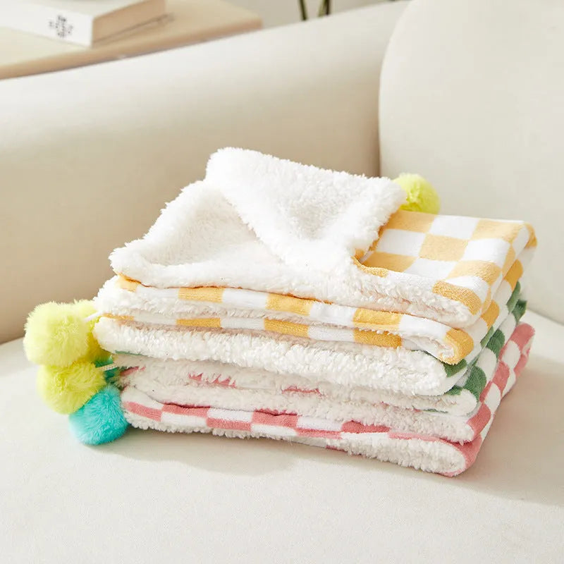 Plush pet blanket with plaid pattern and decorative fur ball in green colour