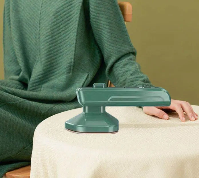 Dark green portable hand-held hanging steam ironing machine with a ceramic panel, shown with a power plug.
