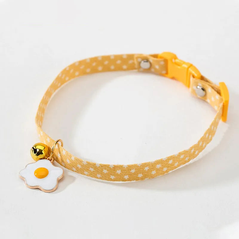 Green adjustable cat collar with a metal bell pendant and a matching bow tie on a white background.