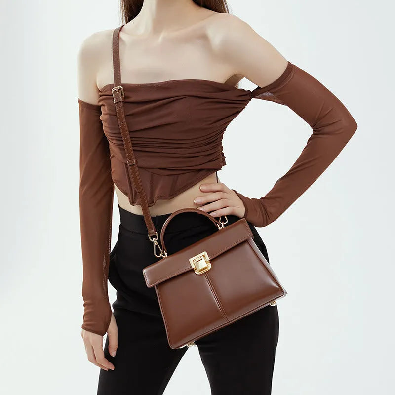 Women's black genuine leather shoulder bag with gold clasp closure showing interior compartments