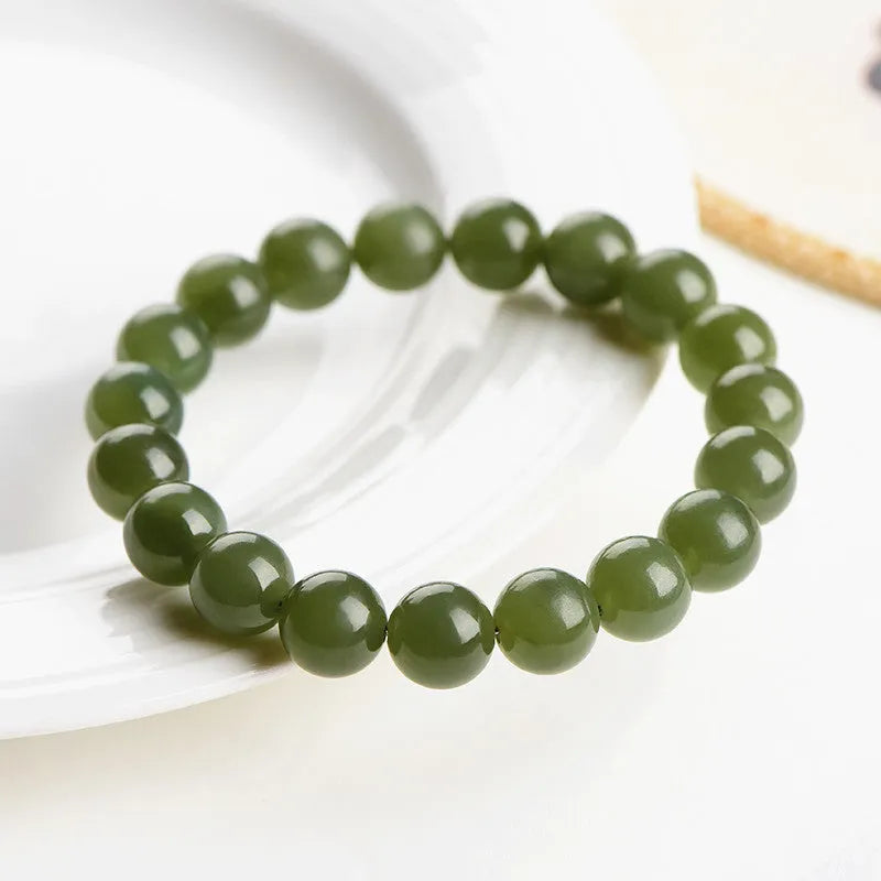 A close-up of a Hetian jade ball bracelet showing polished spherical beads in a clear stone colour, laid flat.