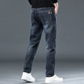 Man wearing slim straight blue grey casual trousers with a loose thin fit and zip fly.