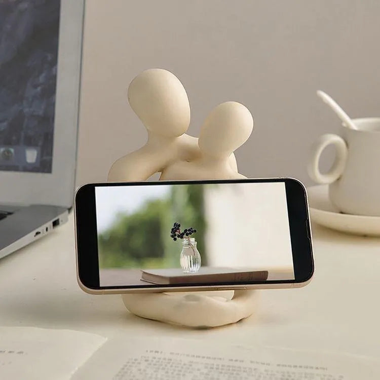 Modern loving couple resin statue in gold or milky white on a wooden shelf.