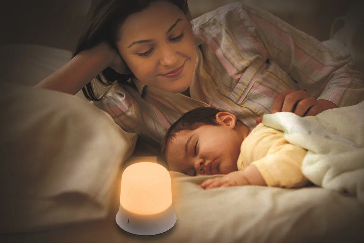 White cylindrical bedside night light with touch controls and motion sensor on a table.